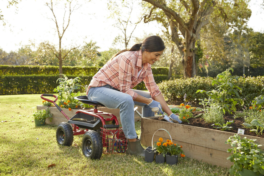 Woman gardening on a rolling seat by a raised garden bed