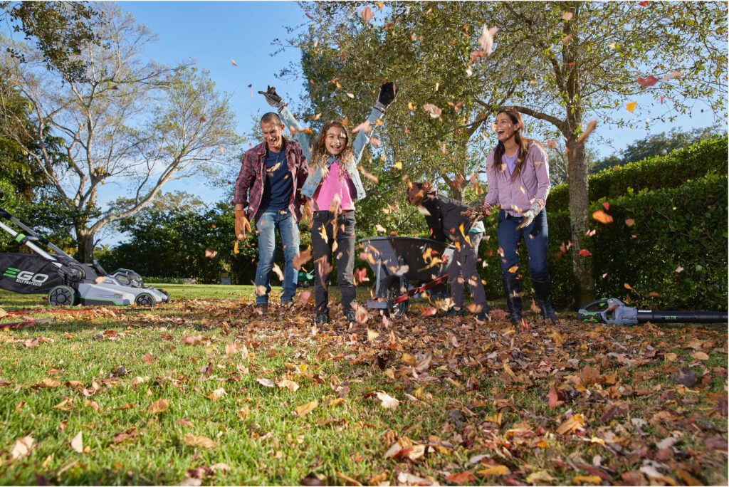 Family playing in autumn leaves in a backyard