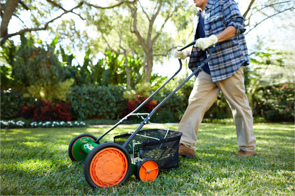 Man using a reel push lawn mower on grass