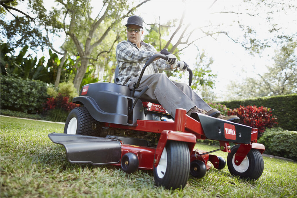 Man riding a zero-turn lawn mower on grass