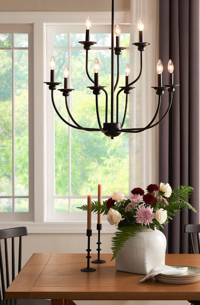 Black chandelier over a dining table by a window