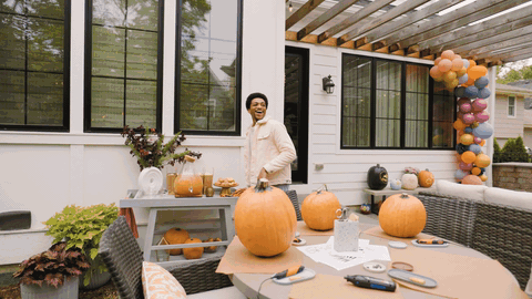 Person carving pumpkins on a decorated fall patio