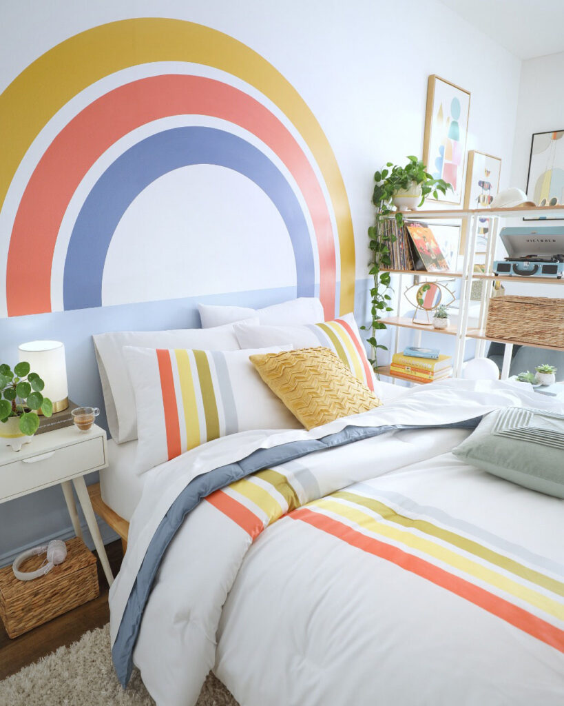Child's bedroom with a rainbow mural and striped bedding