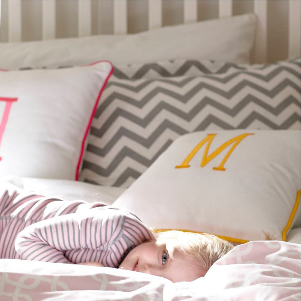 Child sleeping in bed with monogrammed pillows