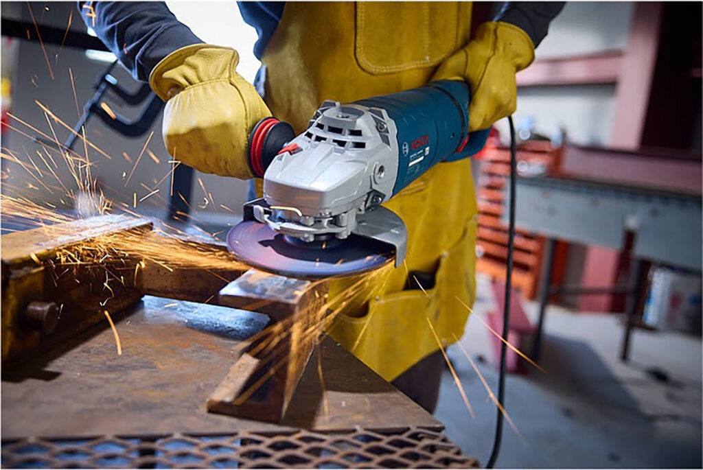 Worker using an angle grinder on metal with sparks