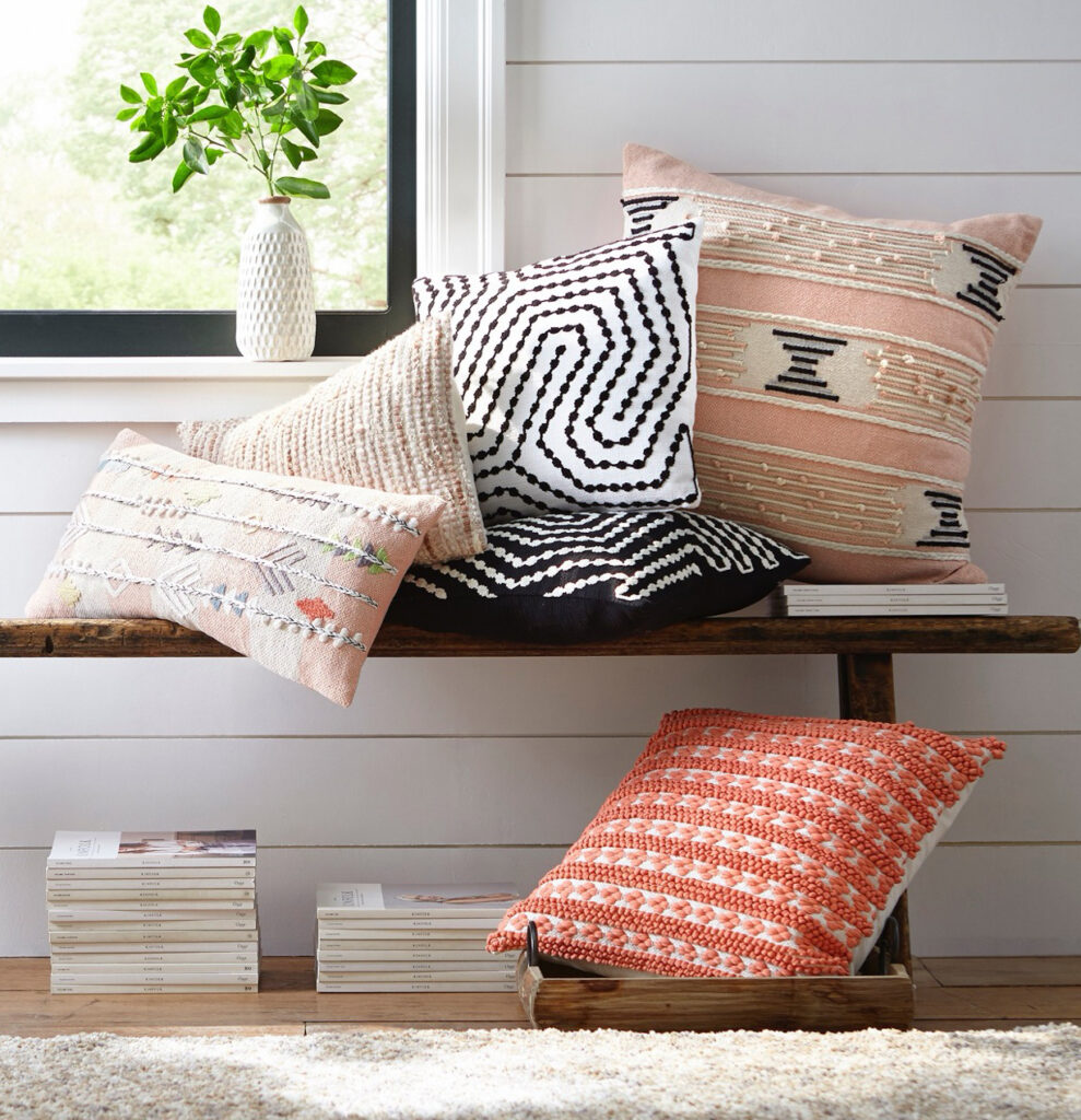Decorative throw pillows on a bench by a wall