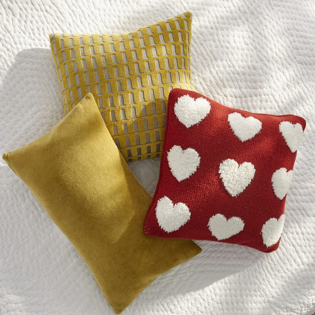 Yellow and red heart-pattern pillows on a bed