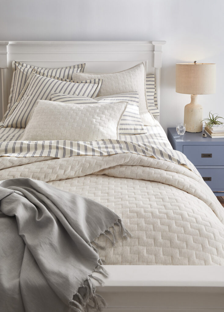 Bed with layered neutral bedding and pillows