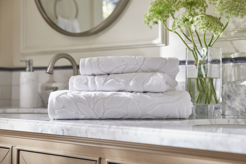 Folded white towels on a bathroom vanity with flowers