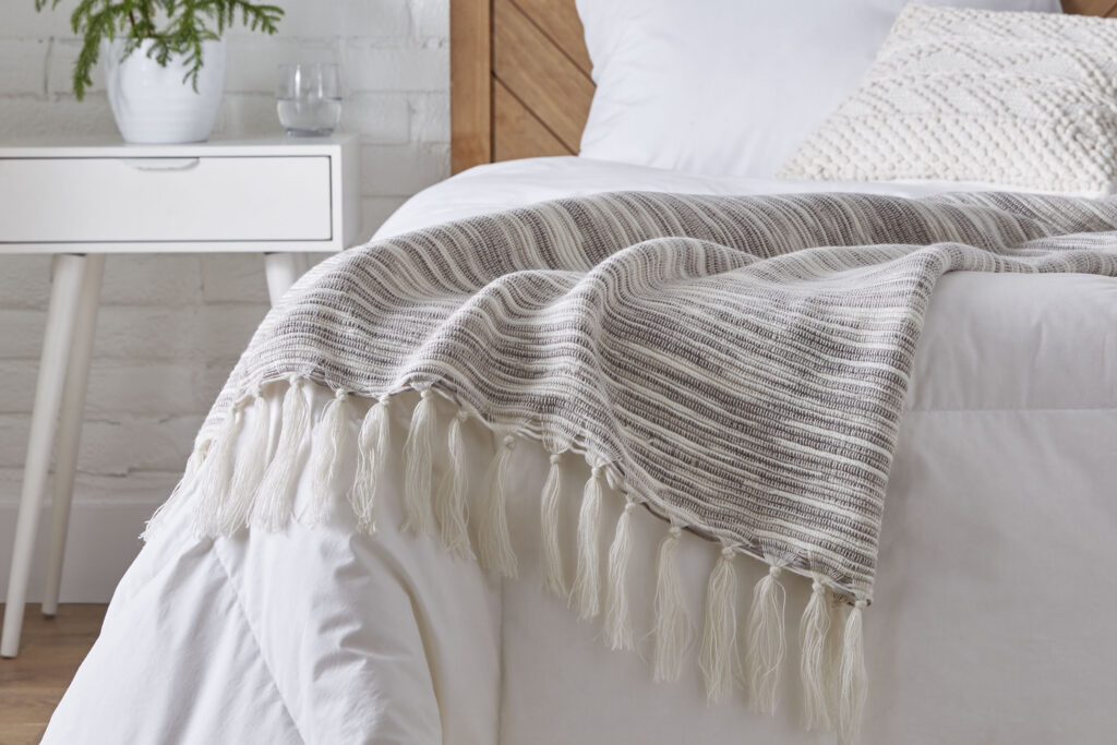 Bed with a ruffled cream blanket and pillows in a bedroom