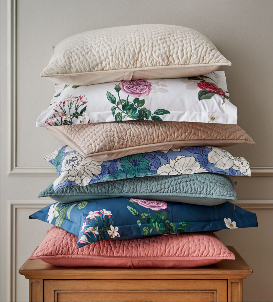Stack of floral pillows on a wooden chest